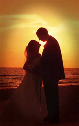 Silhouette of wedding couple kissing at sunset