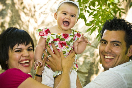 Mum & Dad having fun holding their daughter in the air in this action family pose