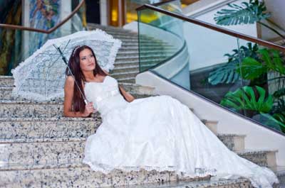A Well Composed Photo Of A Newly-wed Sitting On Some Steps Posing With An Umbrella