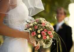 A Bride Holding Her Wedding Bouquet With The Groom Out Of Focus In The Background