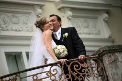 Picture Of The Groom Kissing His Beautiful Wife On A Balcony